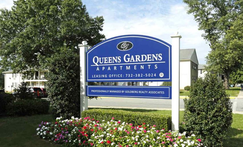 a sign for the queens gardens apartments is shown in front of some flowers